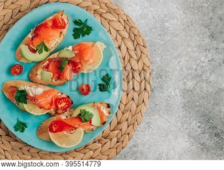 Smoked Salmon Sandwich With Cream Cheese, Lemon, Avoado And Tomato On Gray Background.
