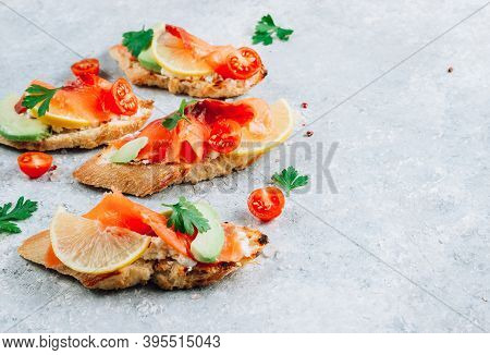 Smoked Salmon Sandwich With Cream Cheese, Lemon, Avoado And Tomato On Gray Background.