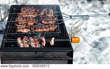 Winter Barbecue Outdoors, Grill Steak And Fork With Meat Over Hot Coals In A Bbq At Campside Cookout