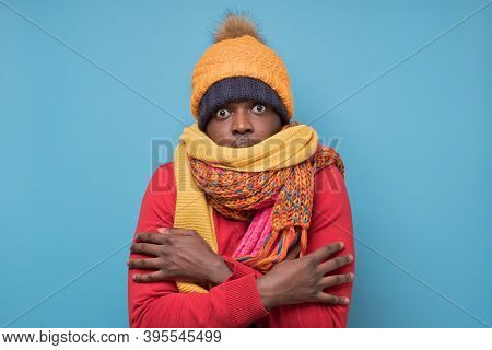African American Mature Man In Yellow Scarf And Hat Freezing In Warm Clothing.