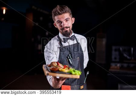 Professional Friendly Flunky Helpfully Holds Plate With Prepared Dish At A Festive Event.