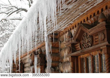 Icicles In Winter. The Old Hut Is Covered With Ice In Winter. Icicles Hang From The Roof.