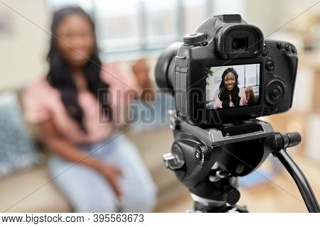 blogging, videoblog and people concept - happy smiling african american female video blogger with camera videoblogging at home