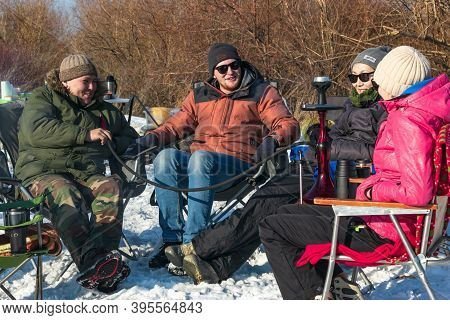 Group Of Friends With Sunglasses Rest On Camping Chairs, Smoking Hookah Outdoors In Campside At Sunn
