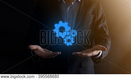 Business Man In Suit Holding Metal Gears And Cogwheels Mechanism Representing Interaction Teamwork C