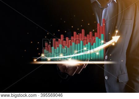 Businessman Holding And Showing A Growing Virtual Hologram Of Statistics, Graph And Chart With Arrow