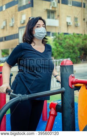 Mature Woman Working Out On An Air Swinger Machine In The Outdoor Fitness Field Near Her Home. She W