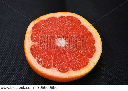 Halves Of Ripe Juicy Grapefruit, Cut In Half, Set On A Black Fabric Background. Delicious And Health