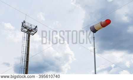 Flying Windsock Wind Vane With Red, White And Blue Lines On Dramatic Sky Background. Test Wind Direc