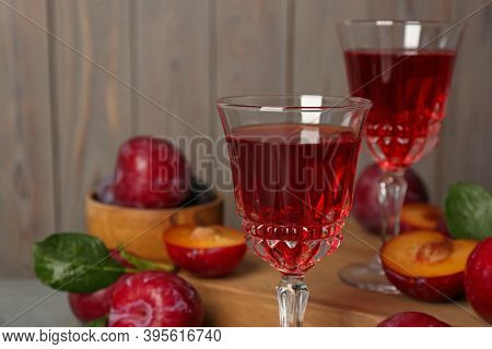 Delicious Plum Liquor On Blurred Background, Closeup. Homemade Strong Alcoholic Beverage