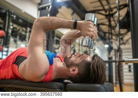 Young Dark-haired Man In Bright Tshirt Working On His Body In Gym