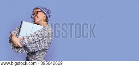 Cheerful Woman With Glasses And Hat Is Embracing A Present Box And Smile On A Blue Studio Wall With 