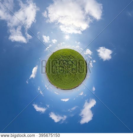 Green Tiny Planet In Blue Sky With Beautiful Clouds. Transformation Of Spherical Panorama 360 Degree