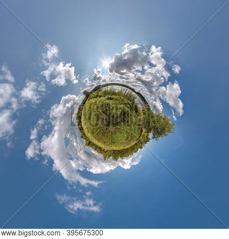 Green Tiny Planet In Blue Sky With Beautiful Clouds. Transformation Of Spherical Panorama 360 Degree