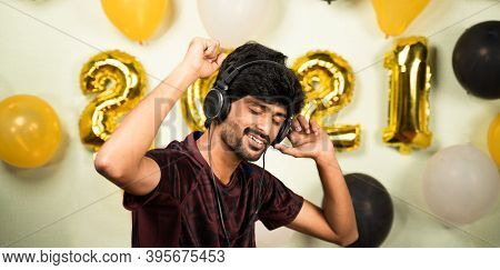 Young Man Enjoying By Listining Music On Headset Over 2021 New Year Decorated Background - Concept O