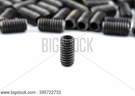 Background Made From A Macro Shot Of One Standing, Black Grub Screw On White Table.