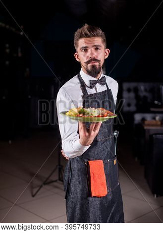 Whiskered Restaurant Employee Carries Appetizing Dish In The Restaurant.