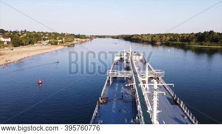 Aerial View Of Cargo Commercial Ship Sailing Down The River Surrounded By Green Forest On A Summer S
