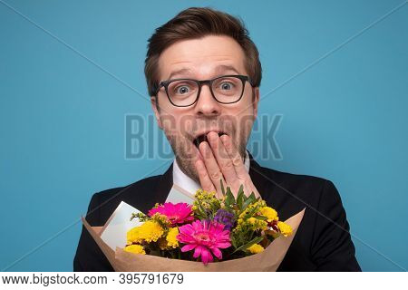 Smiling Man Holding A Bouquet Of Flowers Beong Shocked Or Surprise.