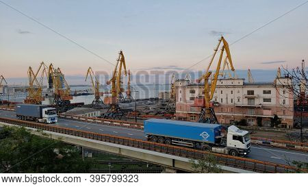 Port Cargo Terminals And Elevated Road With Cargo Vehicle Traffic Of Trailers Carrying Blue Containe