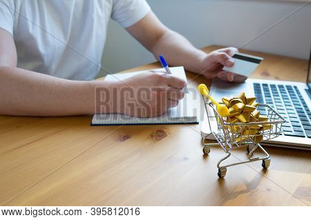 A Man Pays For Purchases On The Internet Without Leaving Home With A Credit Card And Writes Down The