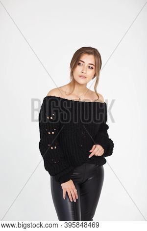 Beautiful Young Woman In A Black Leather Leggings And Black Sweater Posing On A White Background. Po