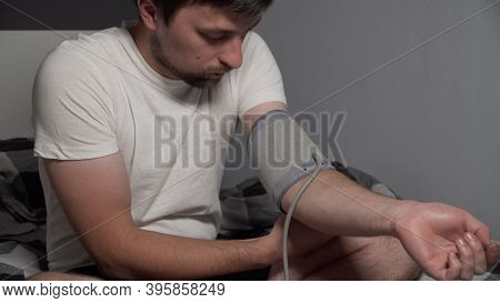 Young Man Measuring Blood Pressure At Home. Hypertensive Patient Performing An Automatic Blood Press