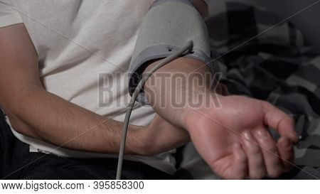 Young Man Measuring Blood Pressure At Home. Hypertensive Patient Performing An Automatic Blood Press