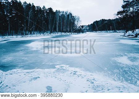 Cracks On The Surface Of The Blue Ice. Frozen Lake In Winter Mountains. It Is Snowing. The Hills Of 