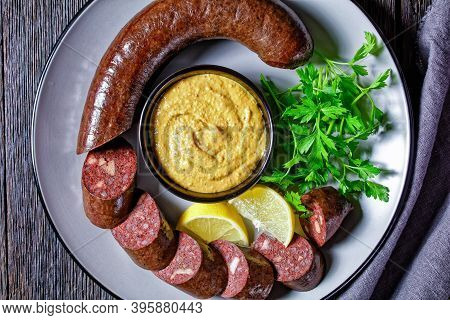 German Blutwurst Or German Blood Sausage Sliced And Served On A Plate With Parsley, Mustard And Lemo