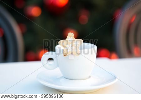 White Porcelain Coffee Cup With Saucer And Wooden Decorative Star With Snowflakes. Blurred Backgroun