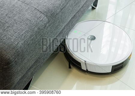 Robotic Vacuum Cleaner Cleaning The Floor Under The Sofa.