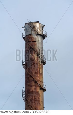 Remains Of An Old Factory. The Round Steel Chimney And The Steel Construction Of The Building Are Cl