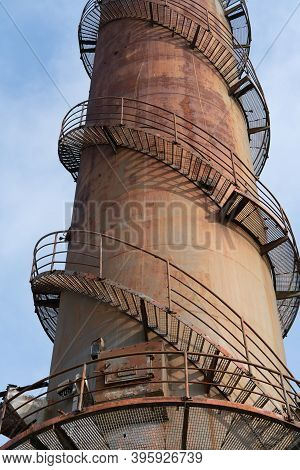 Remains Of An Old Factory. The Round Steel Chimney And The Steel Construction Of The Building Are Cl