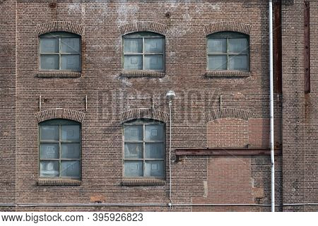 A Fragment Of An Old And Weathered Facade Of An Old Factory, Made Of Masonry, Steel And Wooden Frame