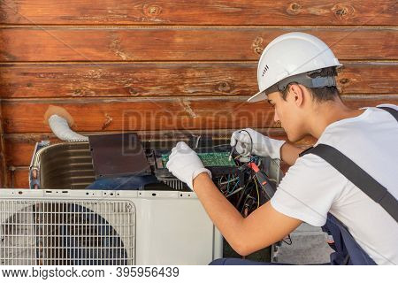 A Young Electrician Repairs An Air Conditioner. Split System Maintenance