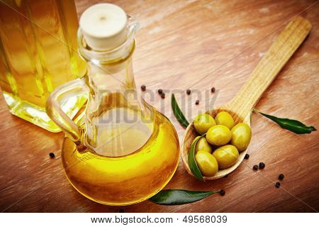 Olive oil with fresh olives on rustic wood