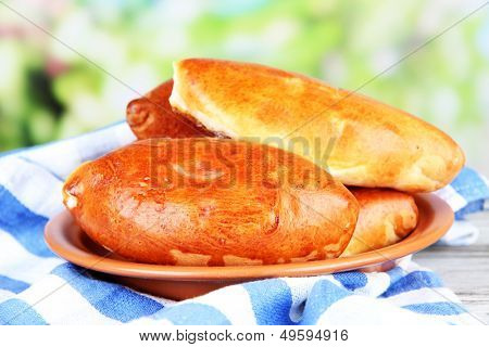 Empanadillas al horno frescos, en mesa de madera, sobre fondo brillante