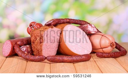 Lot of different sausages on wooden table on natural background