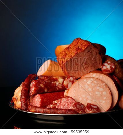Lot of different sausages on salver on dark colorful background