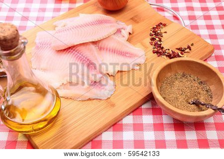 Raw fish tilapia on cutting board and spices