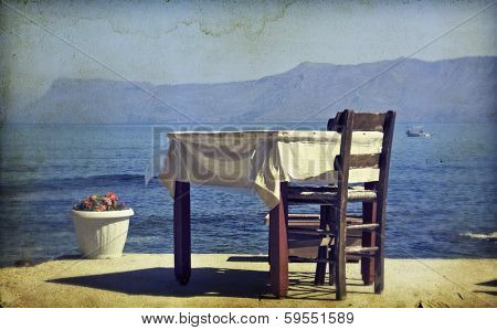 Greek specific - Vintage photo of dining table and chairs set outside on a beach 