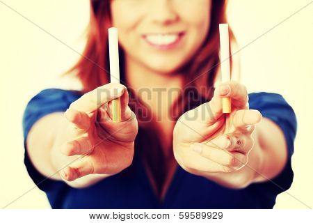Young woman holding in one hand classic cigarette and in other electronic cigarette