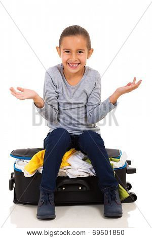 cute little girl sitting on overfilled suitcase