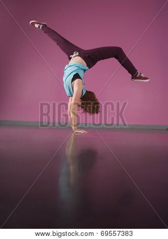 Pretty break dancer doing handstand in the dance studio