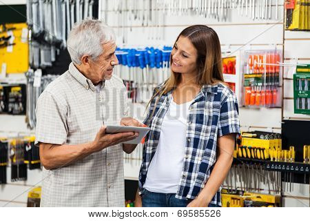 Father and daughter with digital tablet looking at each other in hardware shop