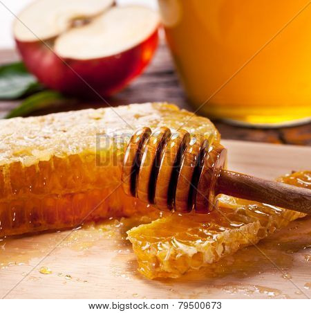 Honeycombs and wooden dripper. Can and apple on the background.