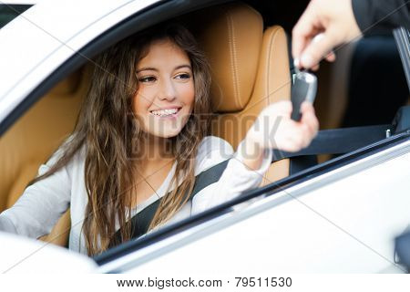 Young woman receiving the keys of her new car