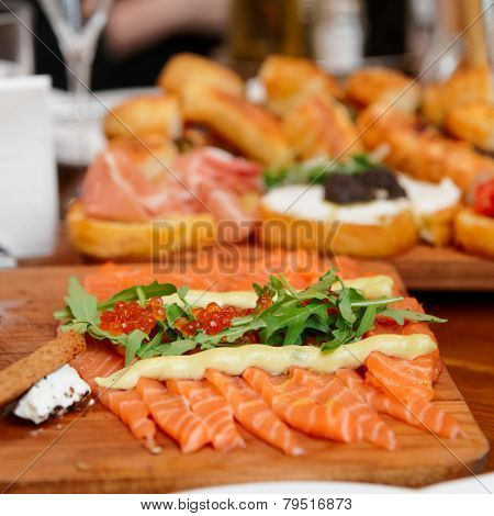Sliced salmon with roe and arugula on table, close-up