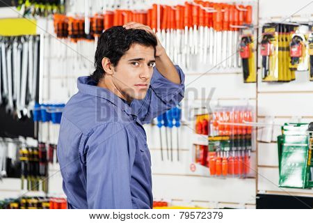 Side view portrait of confused customer with hand on head in hardware shop